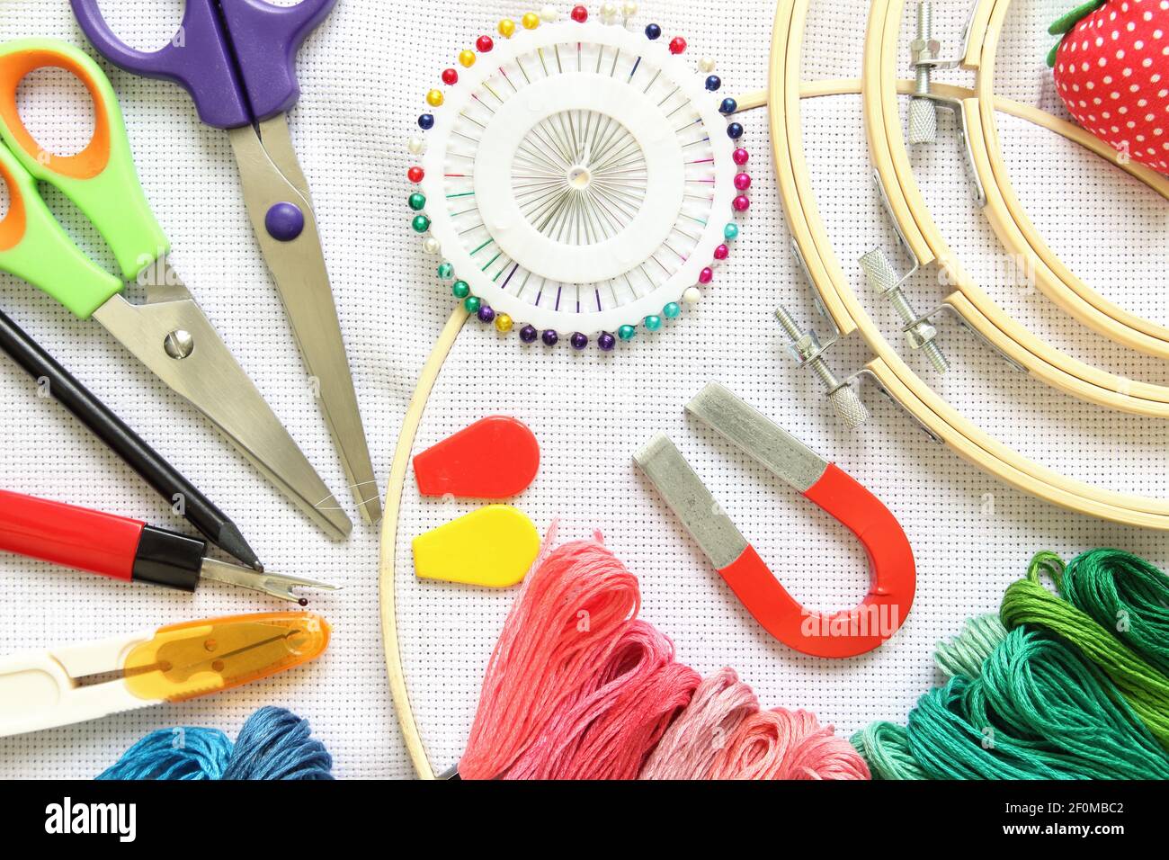 cerchio da ricamo con accessorio per cucire, forbici, fili da ricamo e ago su tela bianca Foto Stock