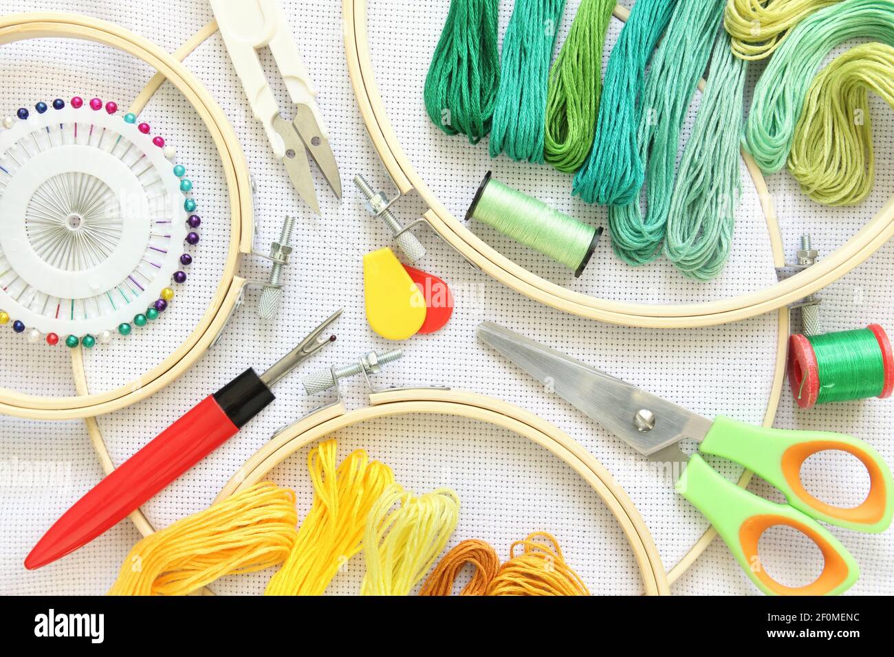 set da ricamo con fili e ago, bottone, forbici e tessuto su telaio Foto Stock