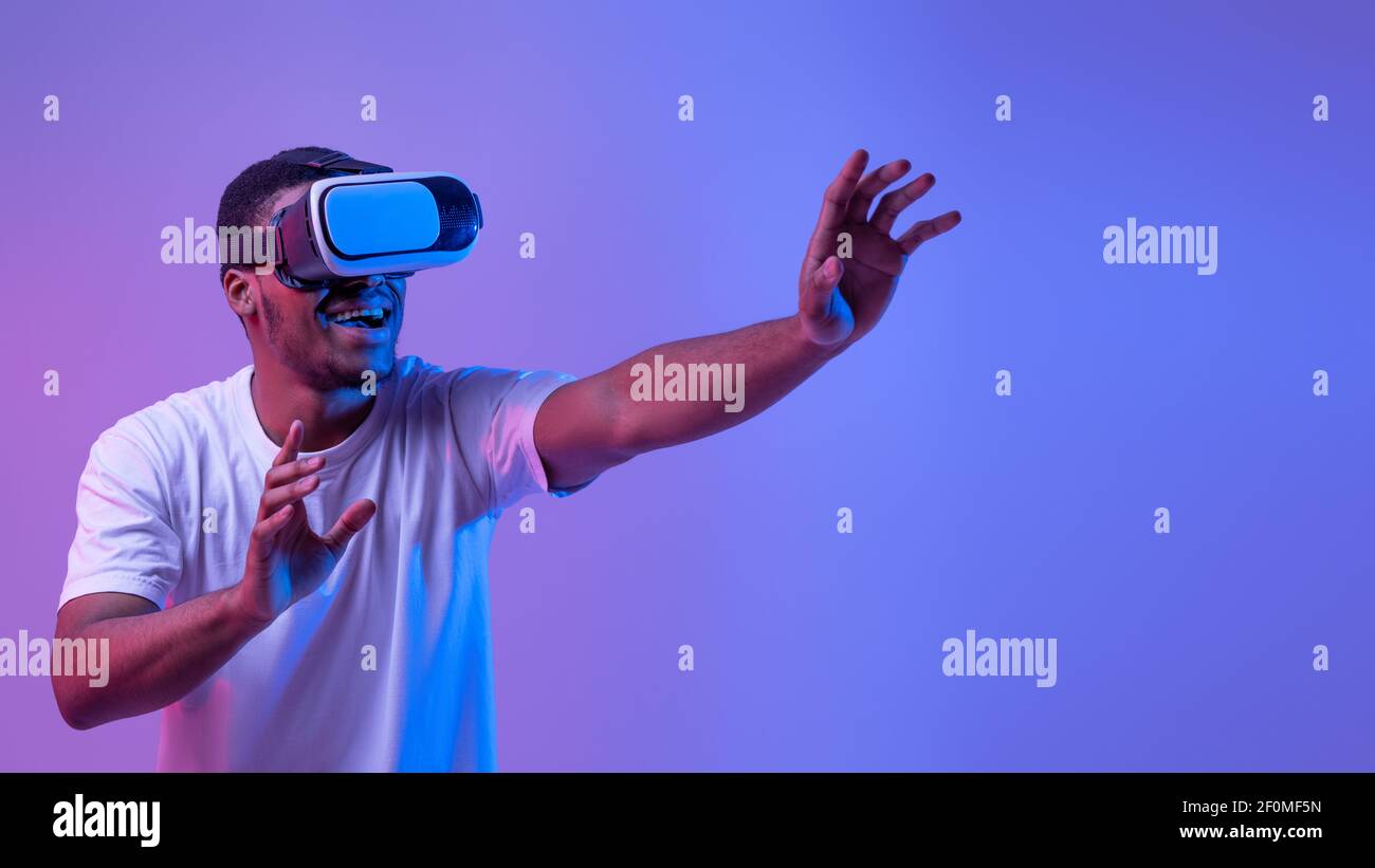 Esperienza virtuale. Eccitato African Man indossare visore VR, giocando videogioco Foto Stock