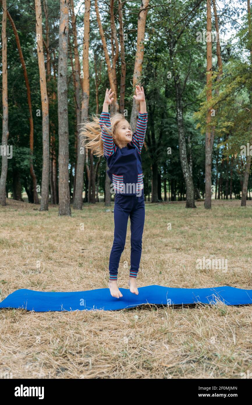 Circuito fitness all'aperto per bambini, giochi di attività estive. Attività all'aperto per bambini. Bambina che fa sport, esercizio fisico, allenamento all'aperto Foto Stock