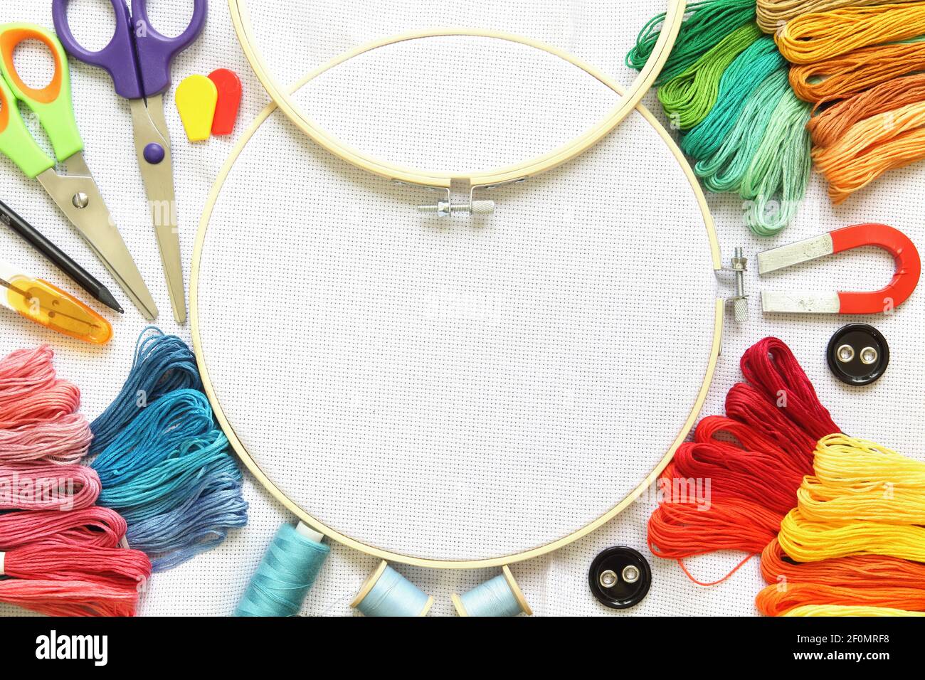 Cerchio da ricamo e accessori multicolore su tela bianca con rocchetti di  filo, ago e forbici Foto stock - Alamy