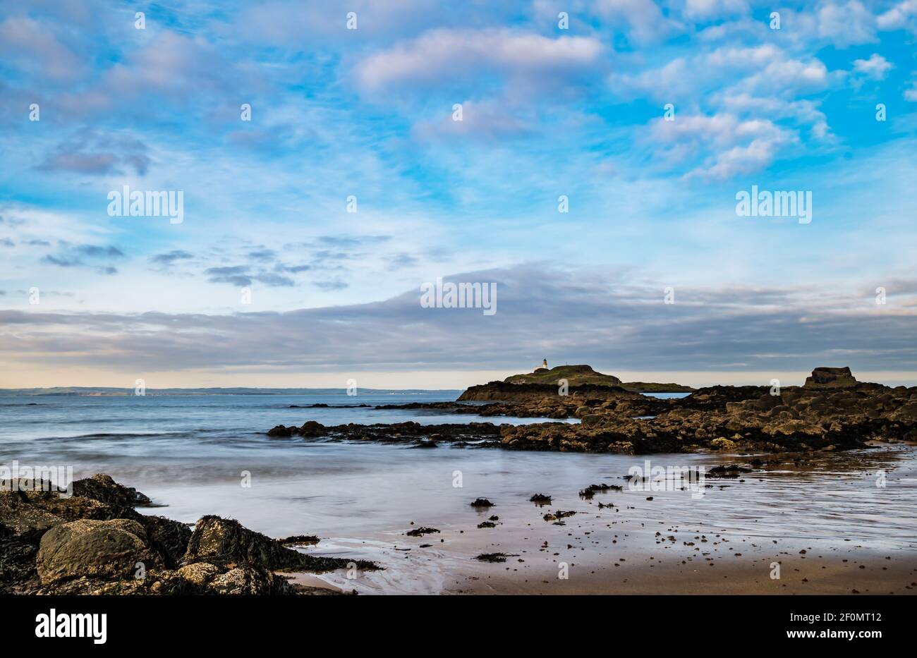 Isola di Fidra all'orizzonte con vista della costa rocciosa dalla spiaggia di Yellowcraig in un giorno di sole con cielo blu, East Lothian, Scozia, Regno Unito Foto Stock