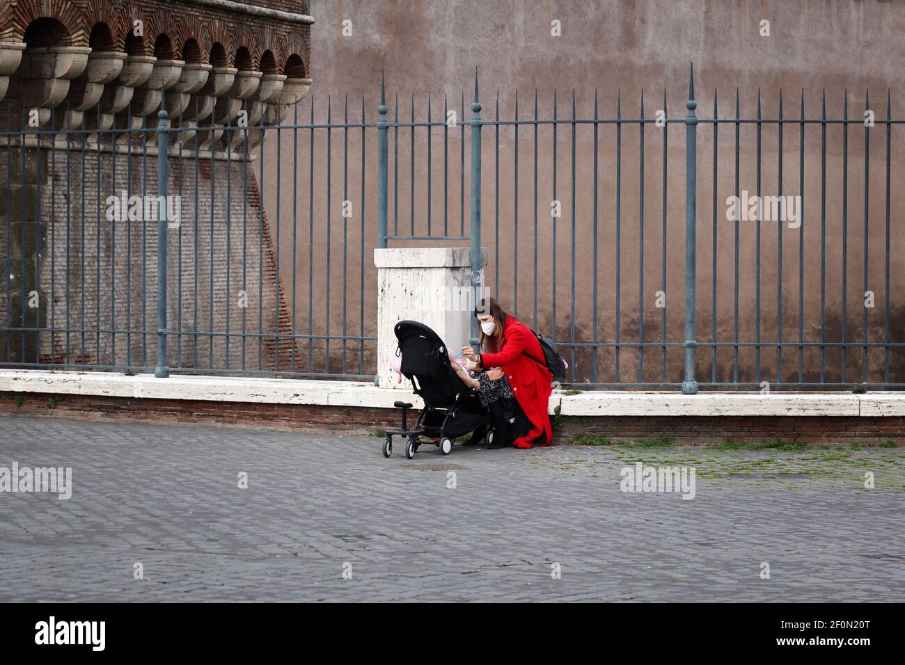 Roma, Italia-6 marzo 2021: Una madre nutre il suo bambino in un passeggino, durante la pandemia del covid-19. Foto Stock