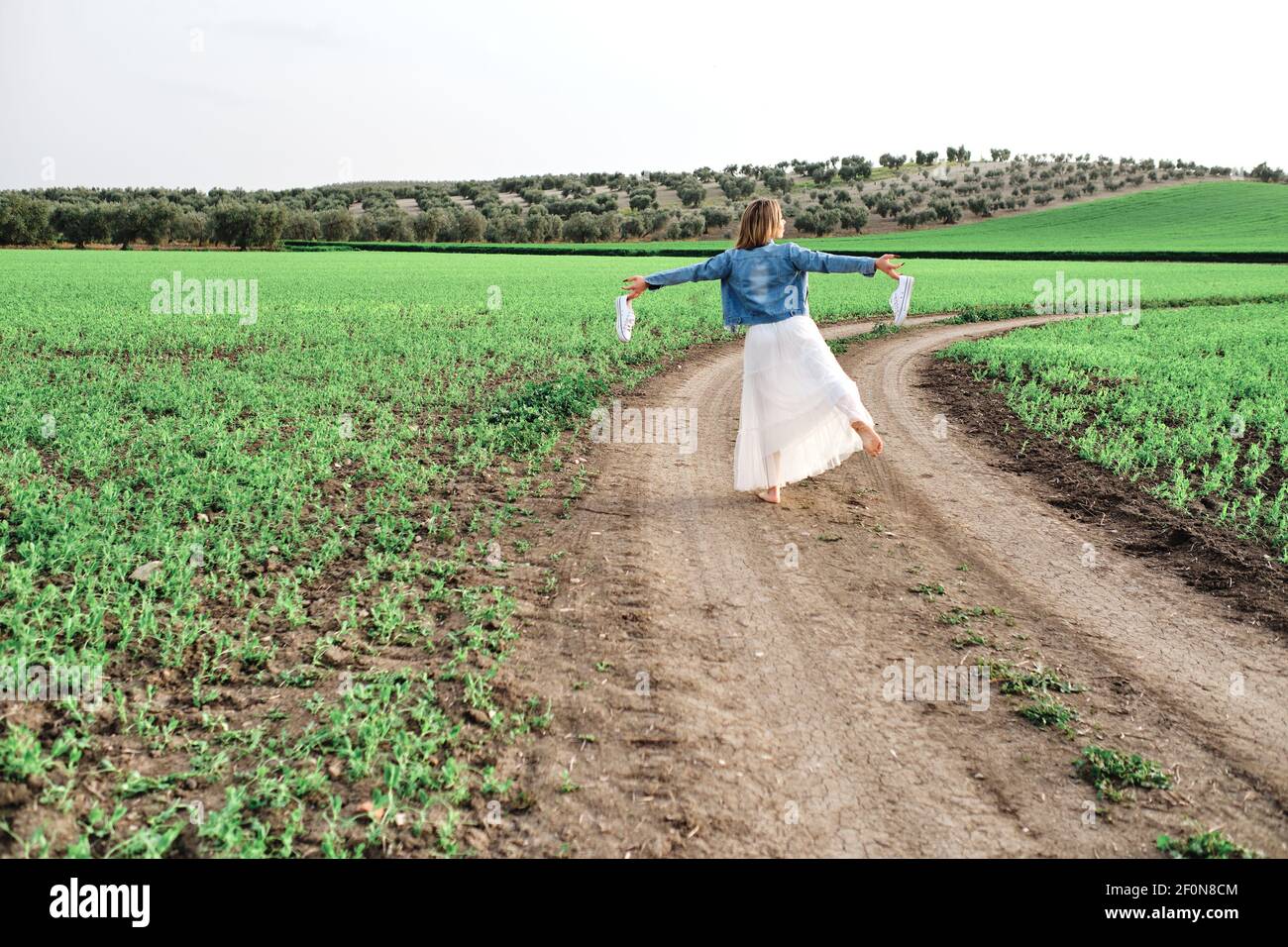 una giovane e bella donna cammina a piedi nudi attraverso la campagna Foto Stock