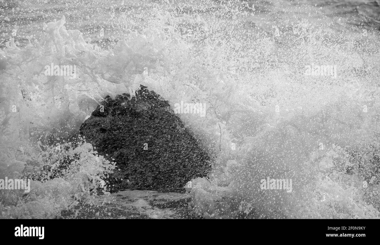 Onde dal canale inglese che si infrangono contro una roccia Una spiaggia a Selsey Foto Stock