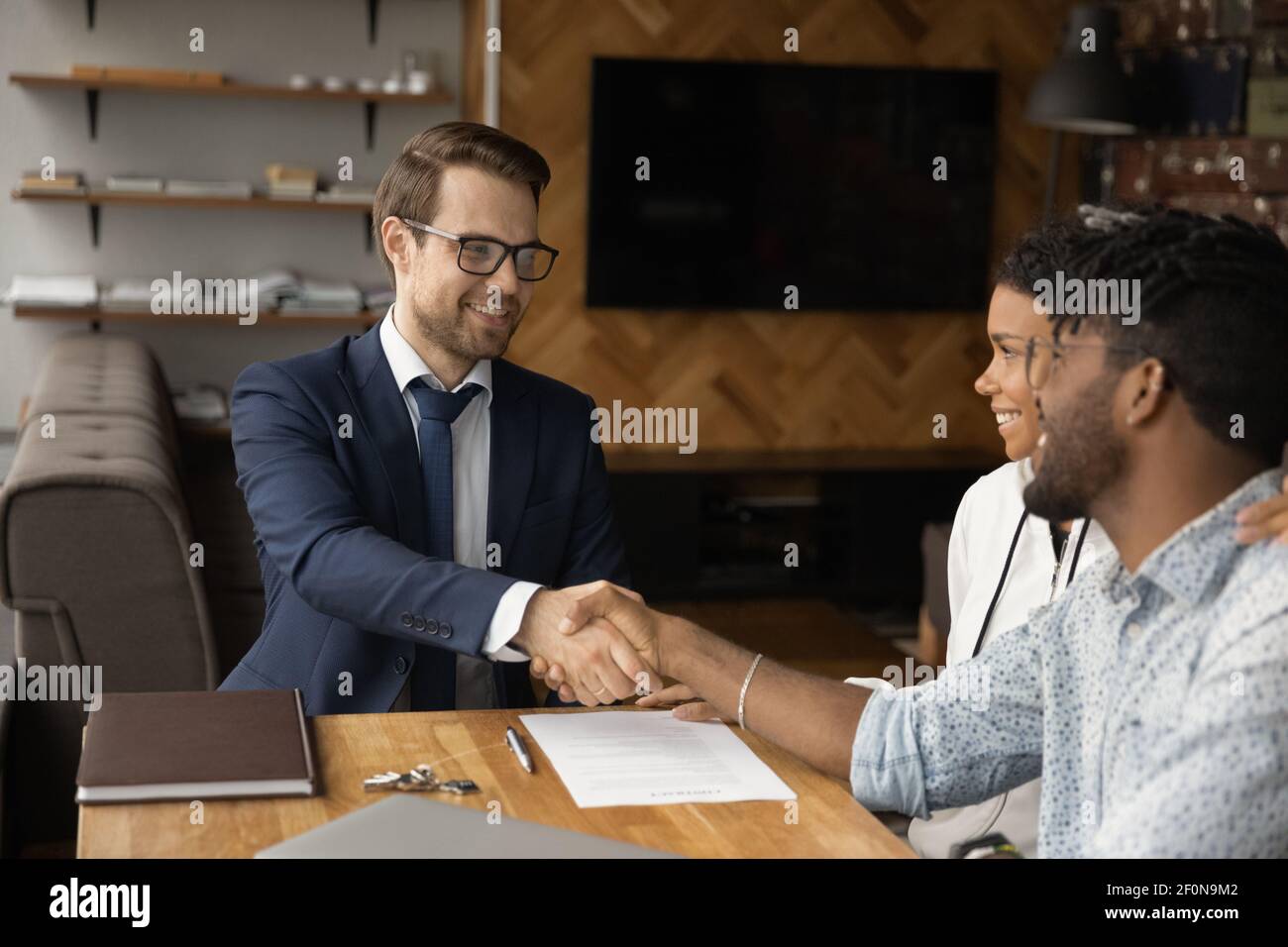 Primo piano sorridente manager e coppia afroamericana scuotendo le mani Foto Stock