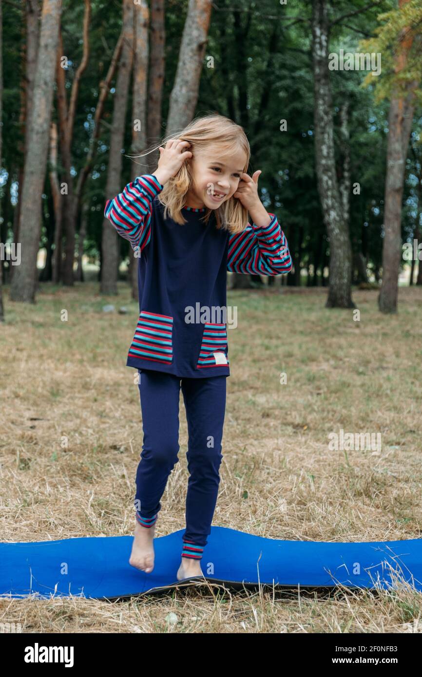 Circuito fitness all'aperto per bambini, giochi di attività estive. Attività all'aperto per bambini. Bambina che fa sport, esercizio fisico, allenamento all'aperto Foto Stock