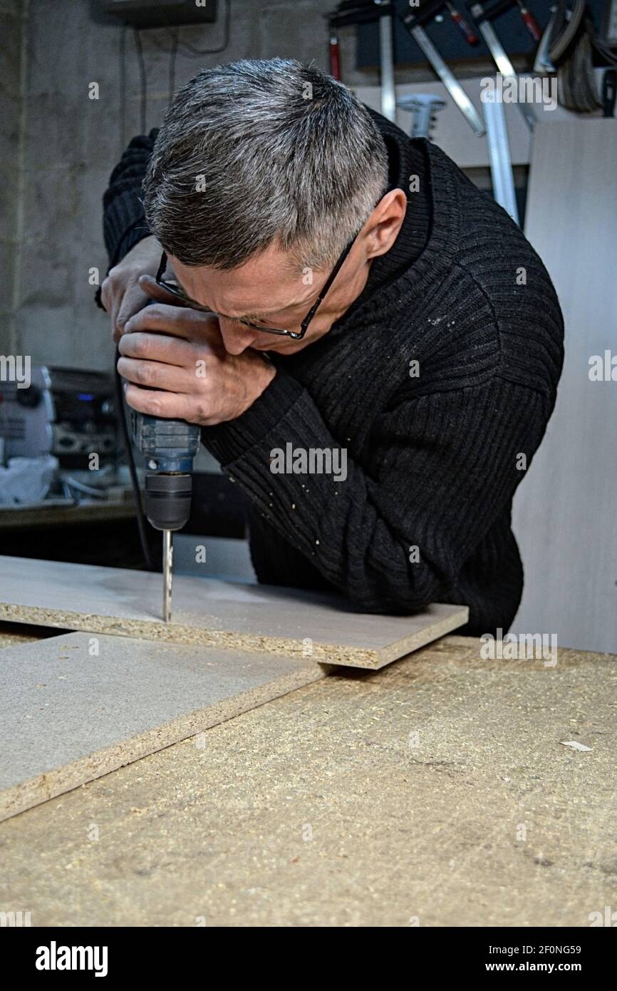 uomo in vetro che lavora con il trapano Foto Stock