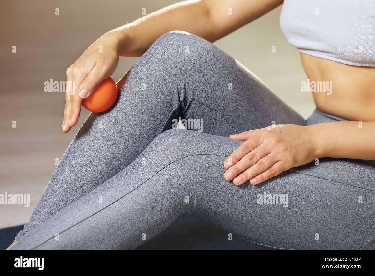 Una donna esegue il rilascio miofasciale dei muscoli della caviglia con una sfera di massaggio a casa. Il concetto di prevenire l'affaticamento delle gambe e l'auto-massaggio. Foto Stock