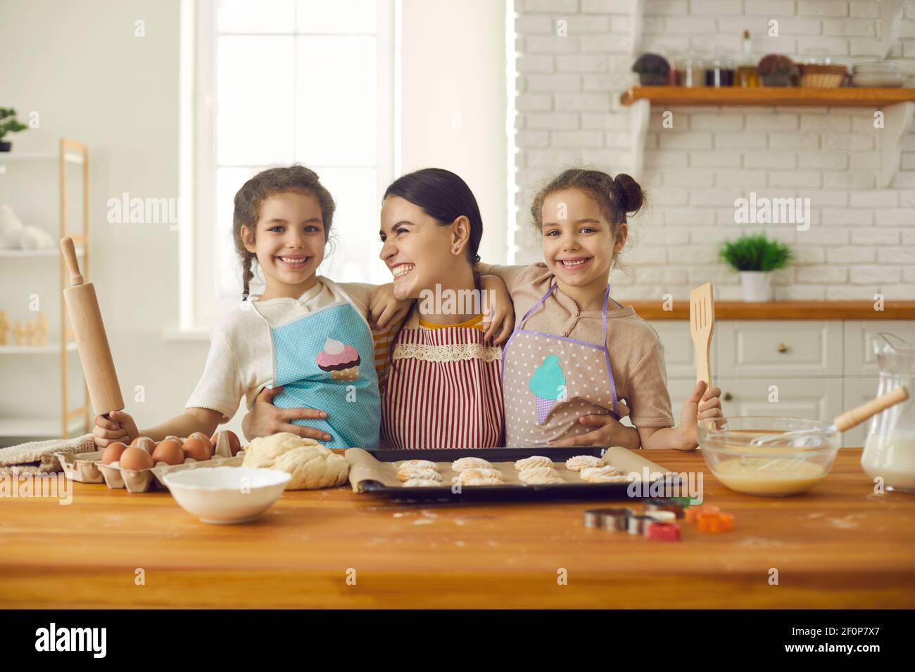 Madre felice e due adorabili figlie che si divertono mentre si cuoce cookie insieme Foto Stock