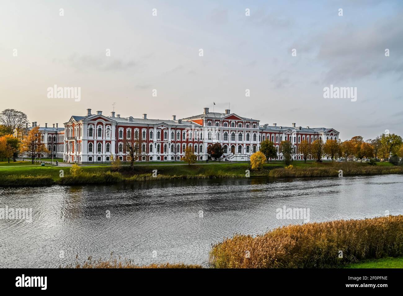 Il primo piano di un grande fiume con le onde nel freddo pomeriggio d'autunno. Vista del bianco palazzo arancione sul lato opposto del fiume riflesso. Foto Stock