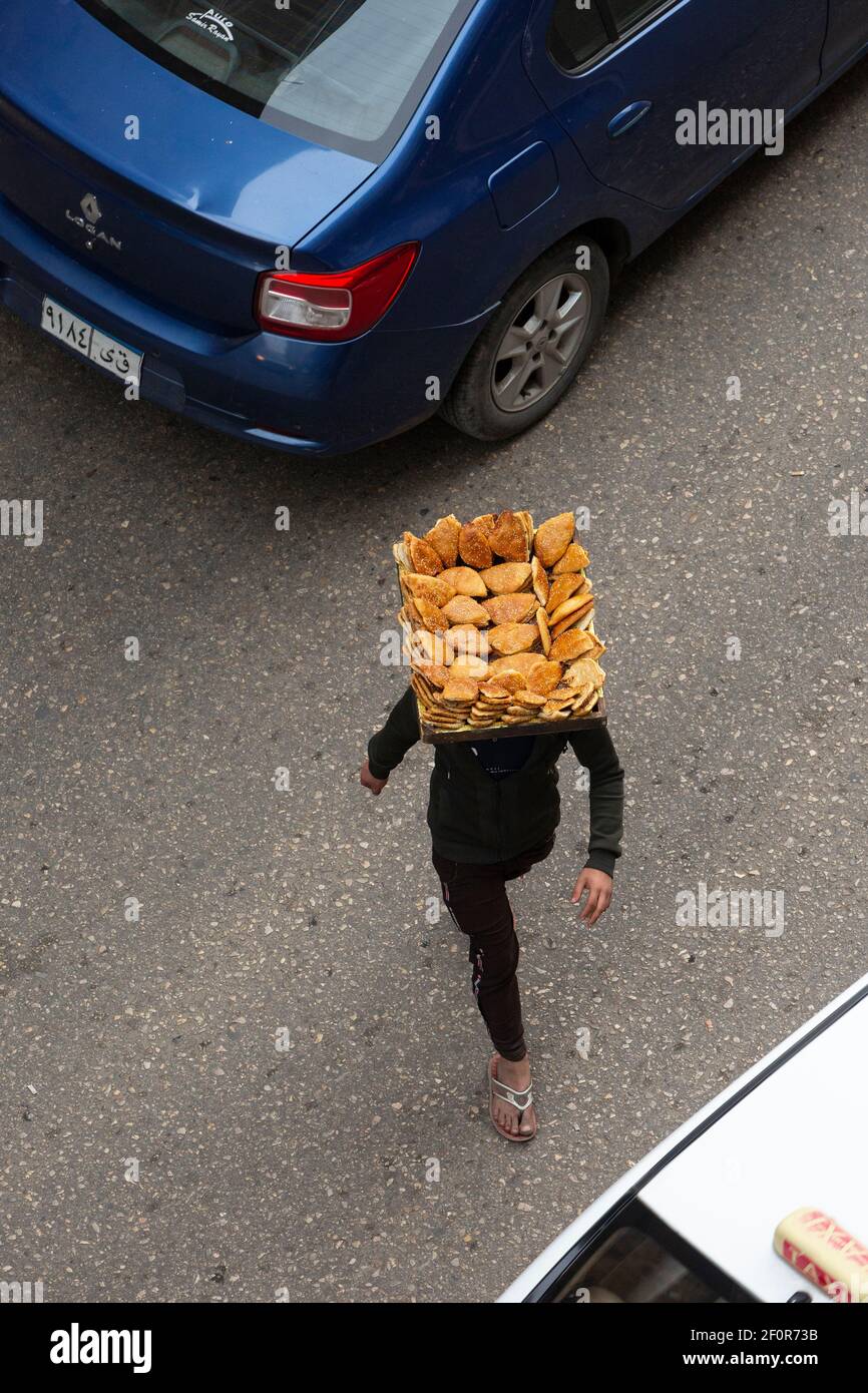 Vista aerea di una persona che attraversa la strada con un vassoio di dolci equilibrati sulla testa, Talaat Harb Street, Downtown Cairo, Egitto Foto Stock