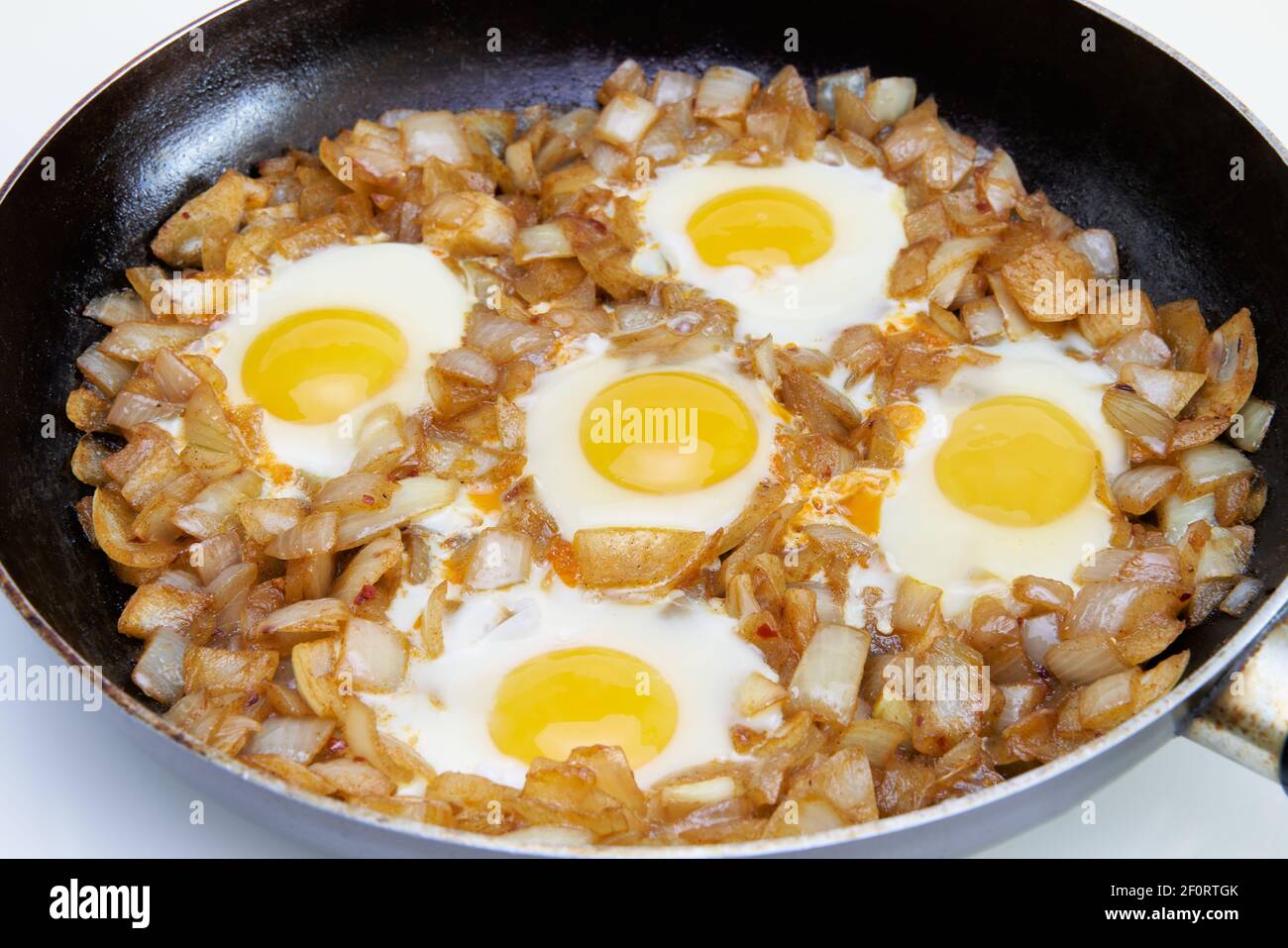 Uova fritte con cipolla su una grande padella Foto Stock