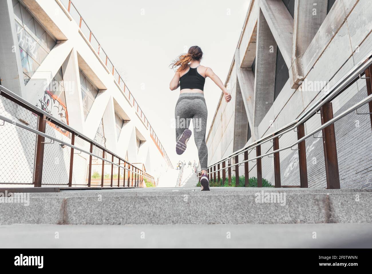 Donna vestita di abbigliamento sportivo che corre sopra le scale della strada Foto Stock