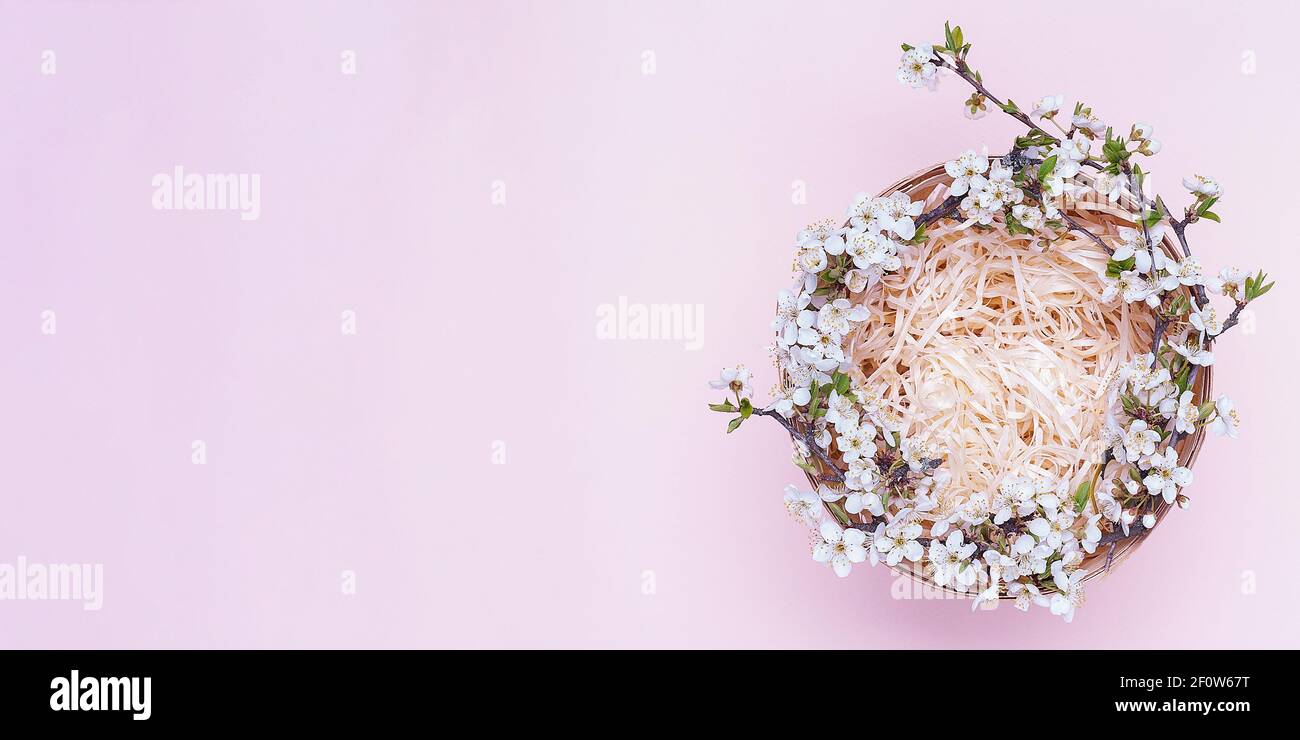 Cestino vuoto con una corona di fiori bianchi su sfondo rosa. Posiziona per il testo. Vista dall'alto Foto Stock