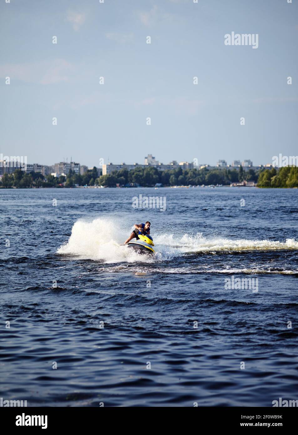 L'uomo forte salta sul jetski sopra l'acqua. Uomo che accelera su moto d'acqua sul lago durante le vacanze estive Foto Stock