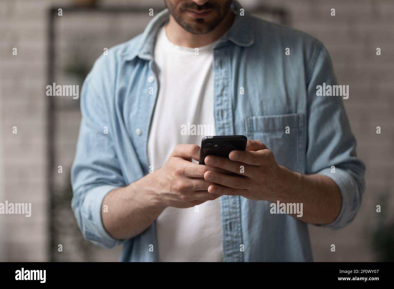 Un'immagine ritagliata di un giovane uomo che tiene utilizzare il moderno telefono cellulare Foto Stock