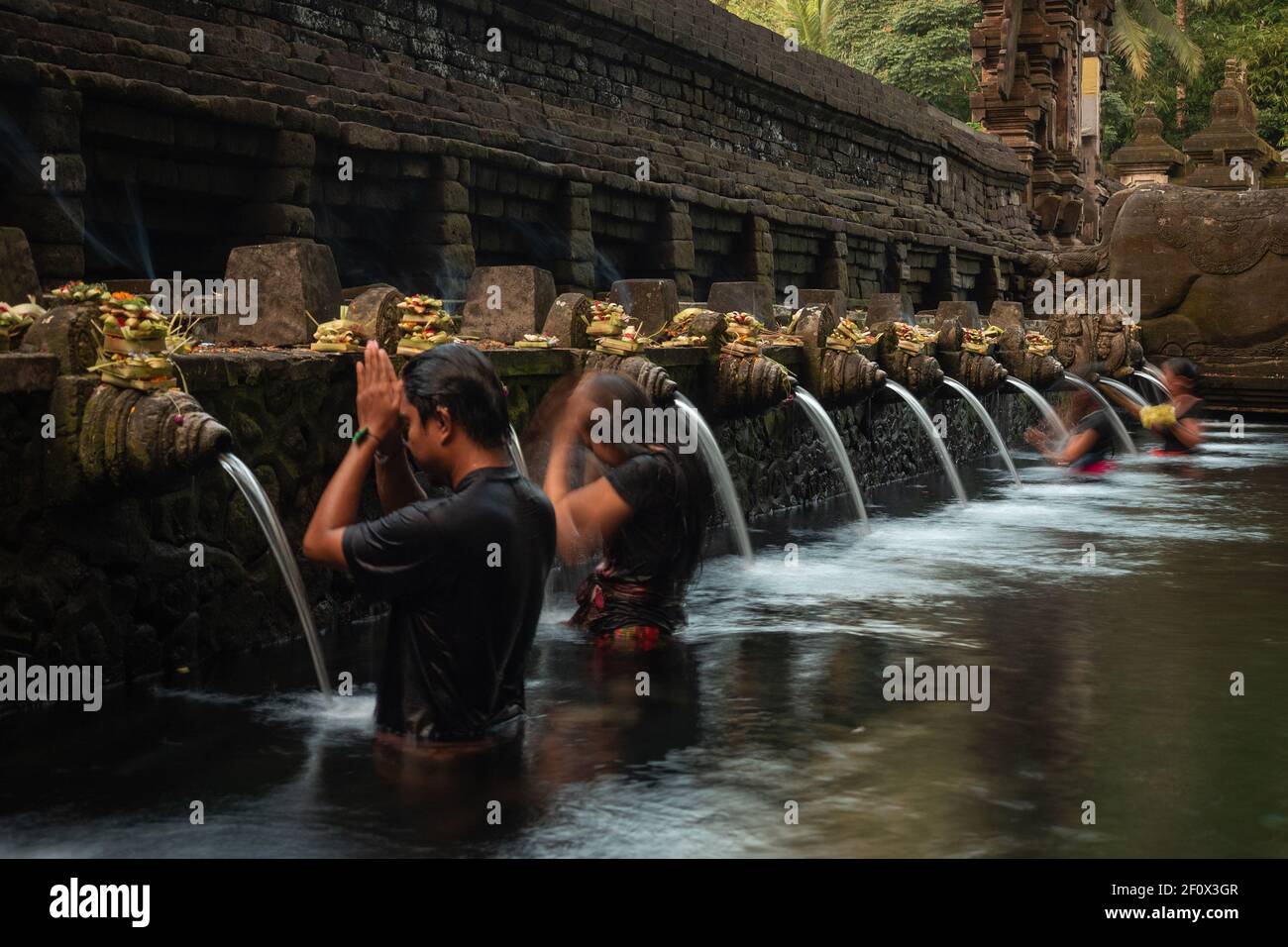 Pellegrini indù balinesi che pregano e fanno il bagno al tempio Tirta Empul delle acque della sorgente Santa vicino alla città di Tampaksiring a Bali, Indonesia. Foto Stock