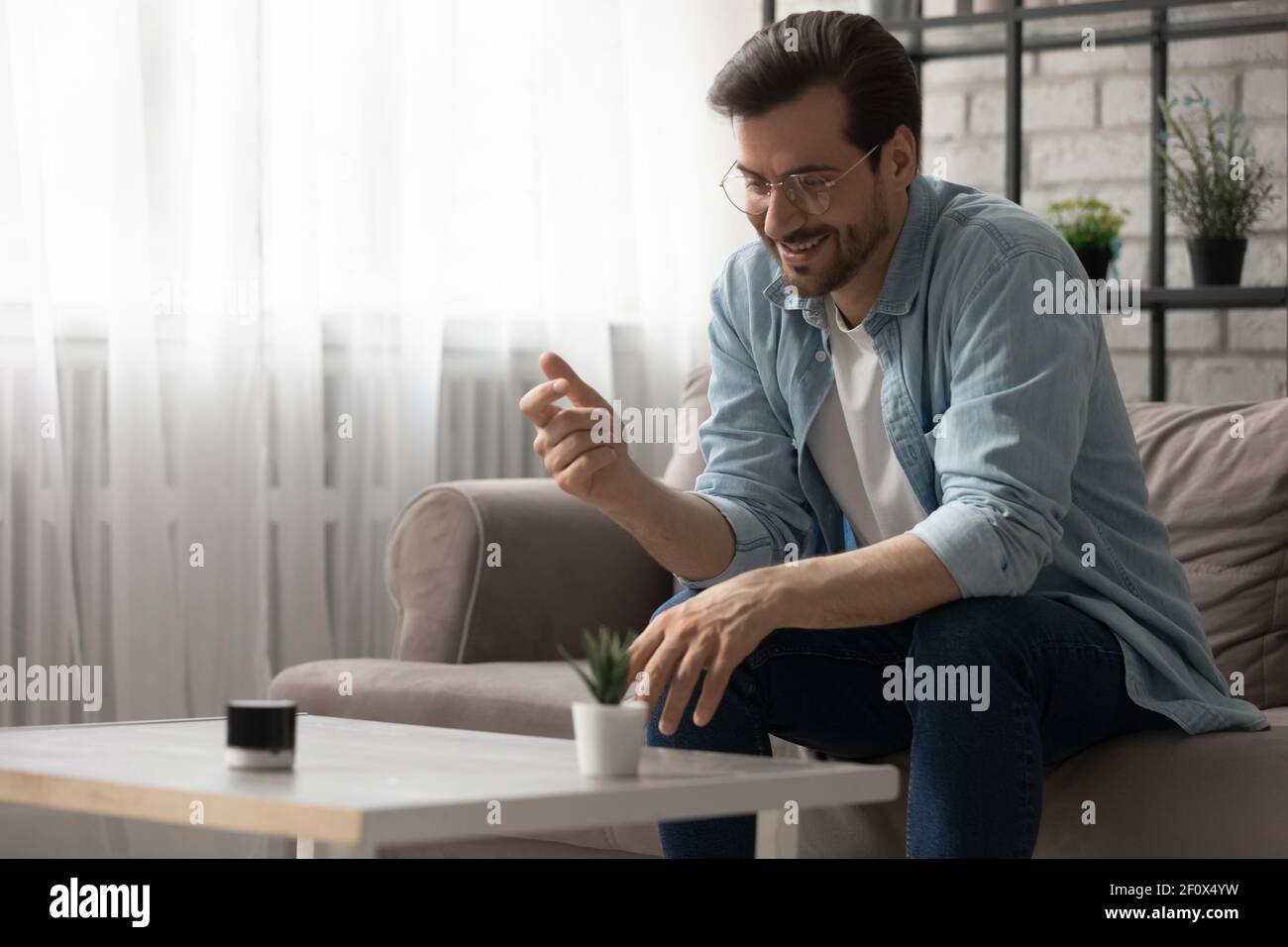 Sorridente ragazzo casual che utilizza un gadget di assistente virtuale digitale intelligente portatile Foto Stock