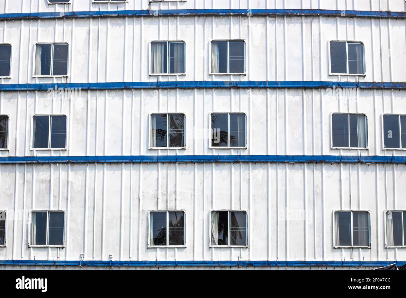 Facciata in ferro di una nave con finestre, un hotel abbandonato in Asia, un edificio non residenziale Foto Stock