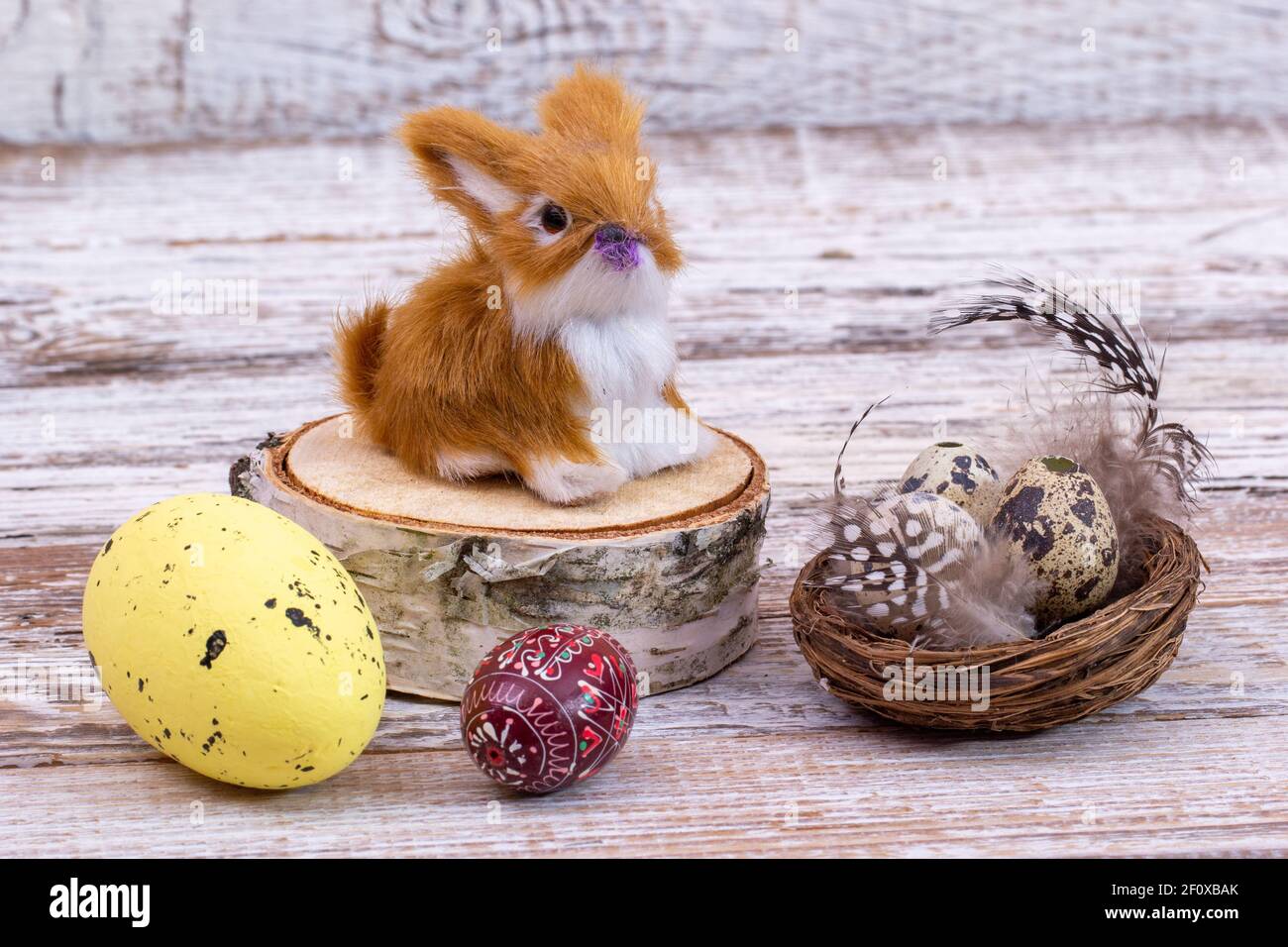 Coniglio di Pasqua su un moncone con uova di Pasqua in un cestino con piume. Foto Stock