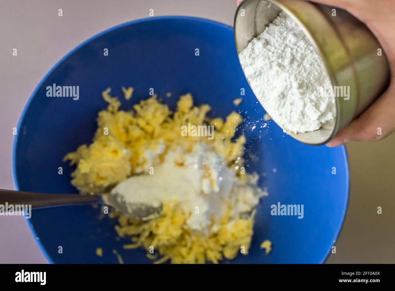 La mano aggiunge zucchero in polvere nel burro Foto Stock