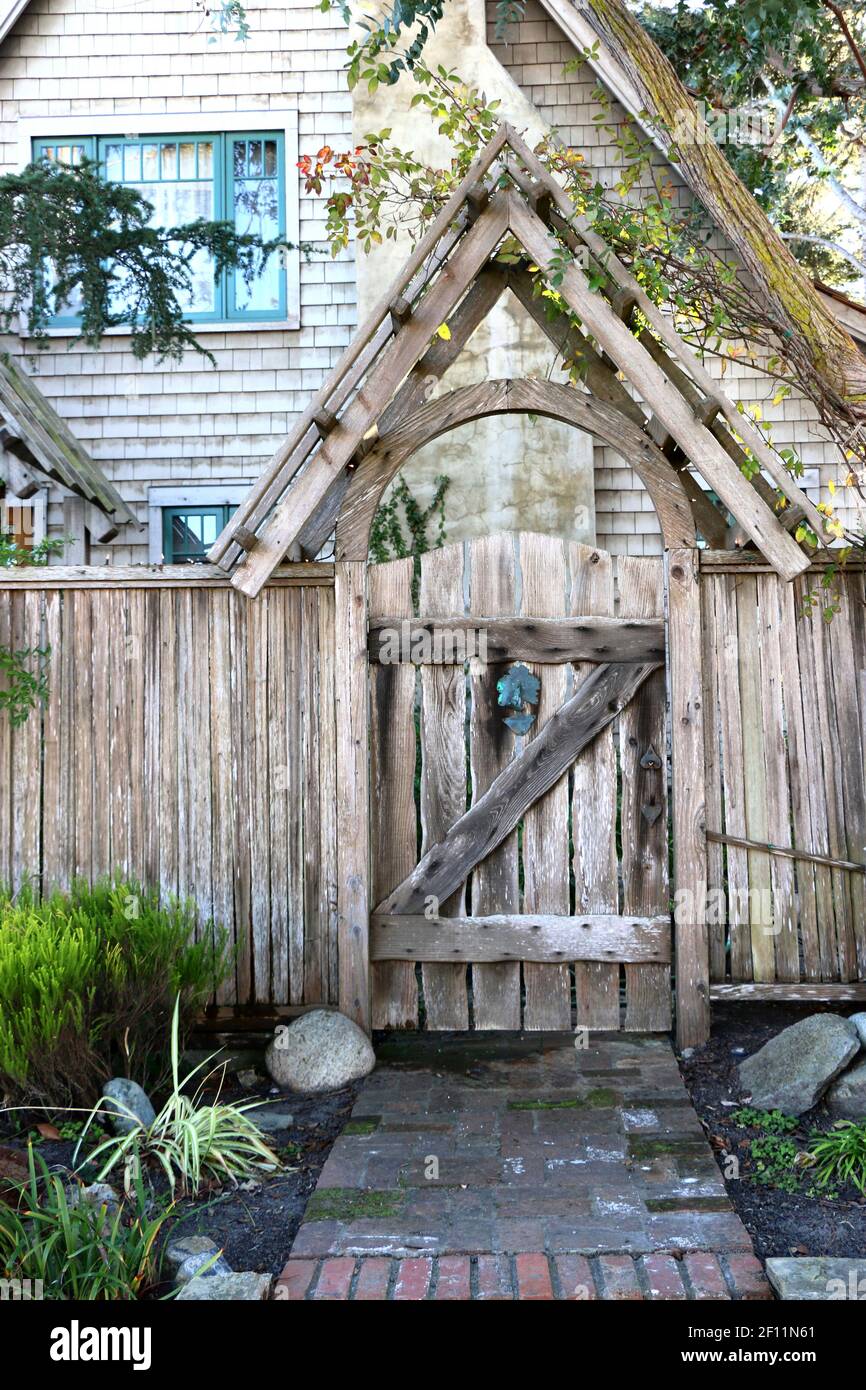 Questo caratteristico cancello di legno intemperie crea un'entrata stravagante al giardino di una casa con travi di cedro. Il design DEL telaio A rispecchia l'architettura di Foto Stock