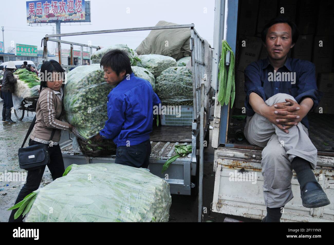 Due agricoltori stanno scaricando il loro camion mentre il loro vicino è seduto in attesa dei clienti. (Foto di Raphael Fournier/Sipa USA) Foto Stock