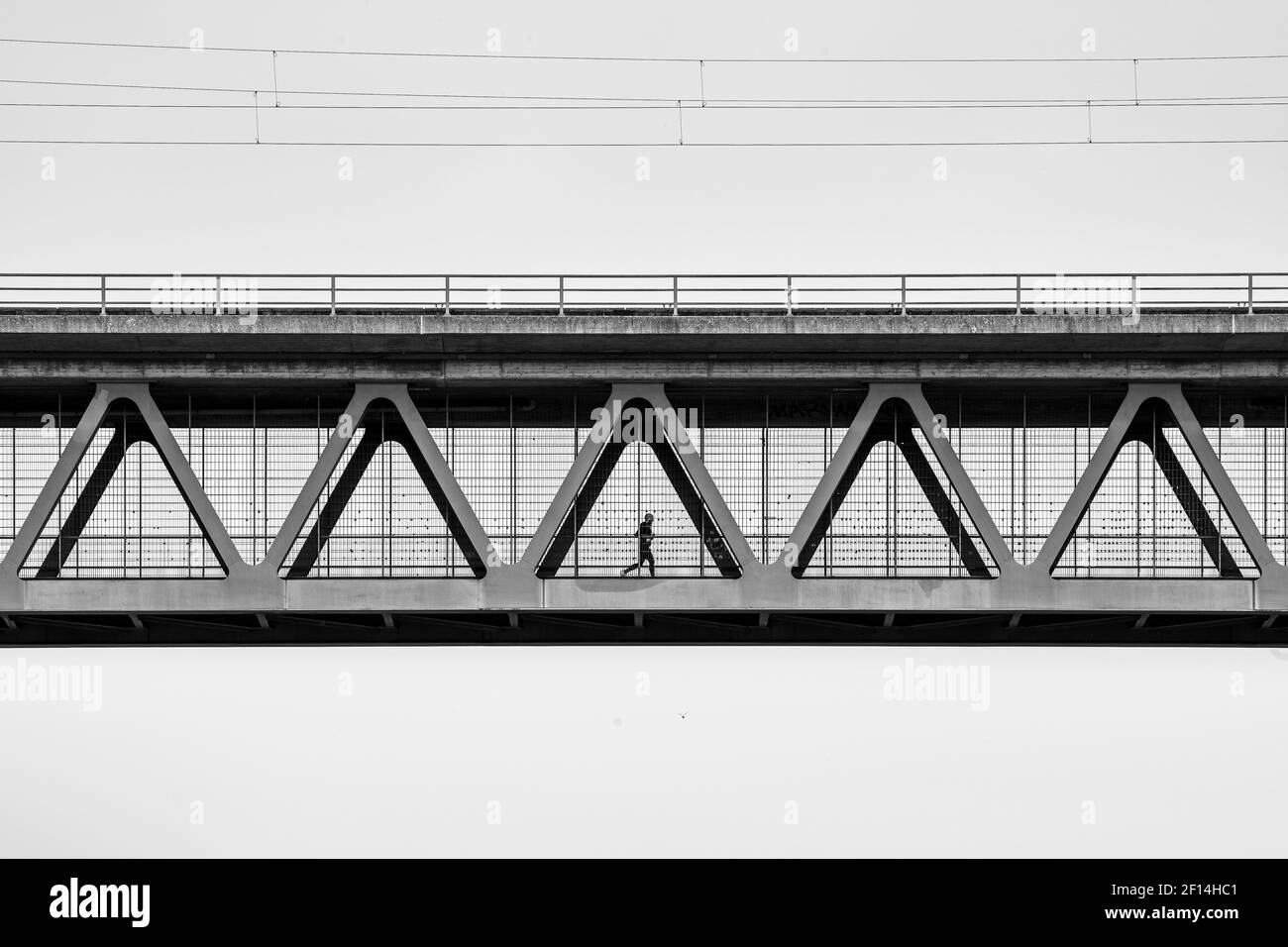 Un uomo sta facendo jogging al contrasto di metallo di un ponte di ferro Foto Stock