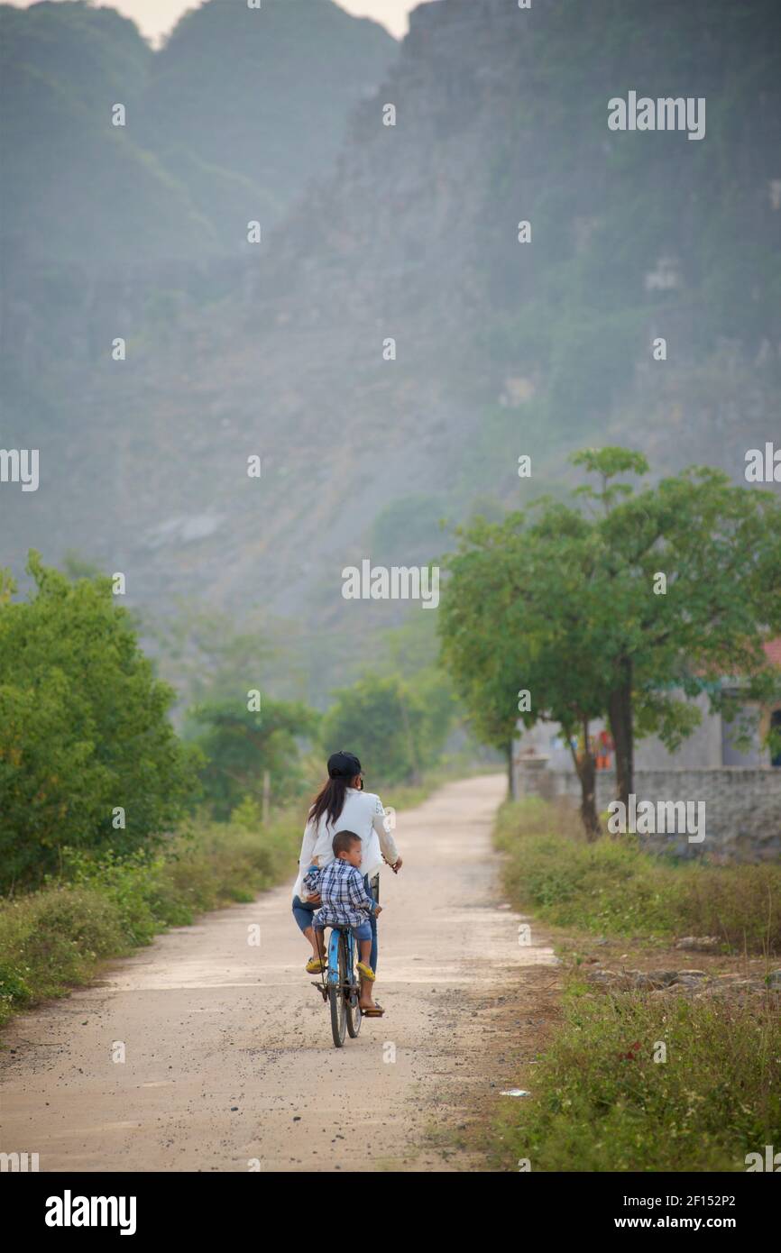 Madre vietnamita e bambino in bicicletta, Hang Mua / Tam Coc, vicino a Ninh Binh, Vietnam. Foto Stock