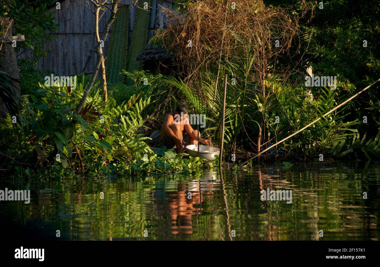 L'uomo si lava in acqua sulla riva di un canale, vicino a Can Tho, Delta del Mekong, Vietnam Foto Stock