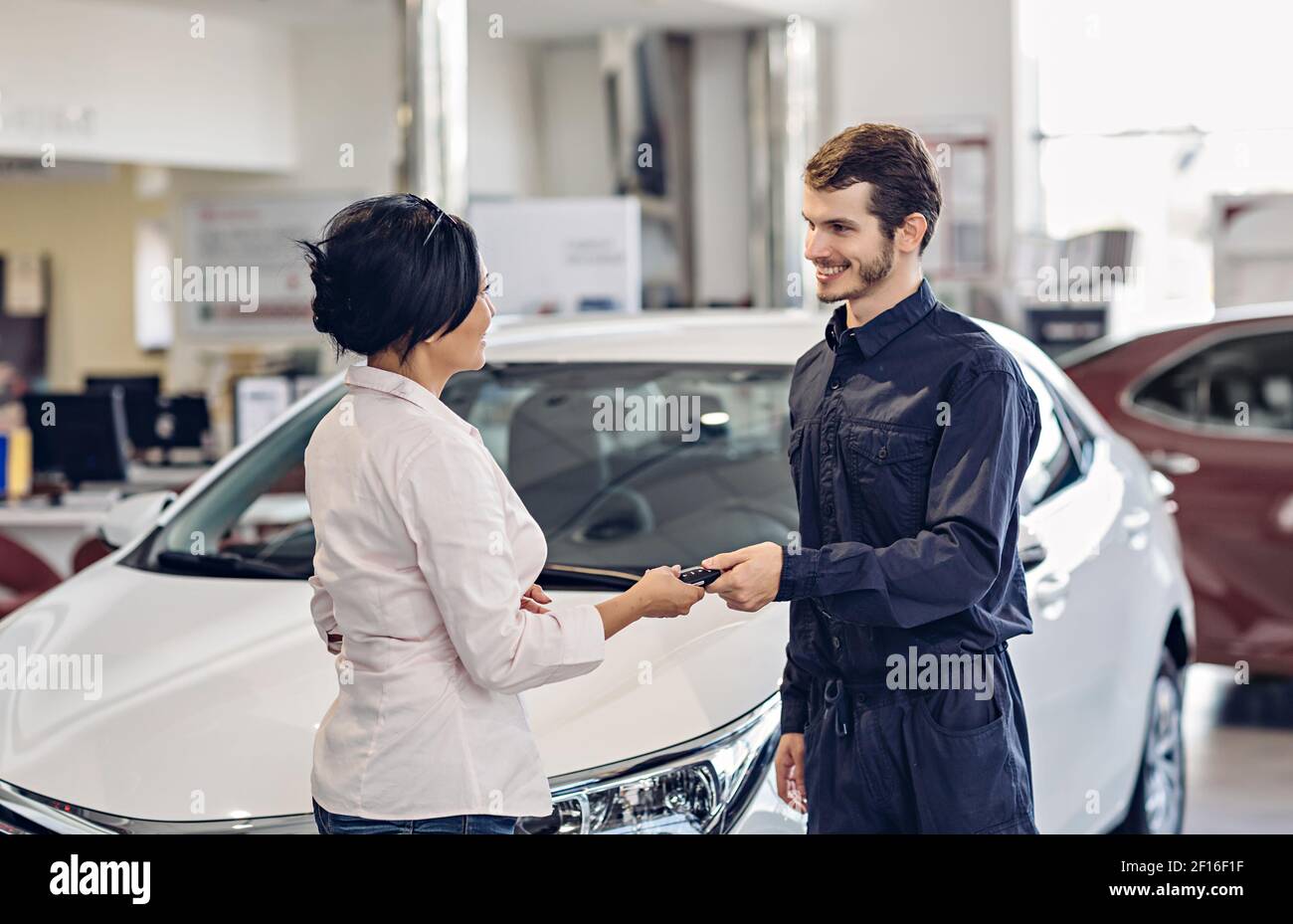 Scena del centro di assistenza auto. Il meccanico che dà la chiave dell'automobile al cliente Foto Stock