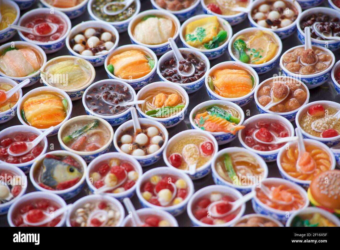 Esposizione di piccole ciotole di alimenti di simulazione che sono venduti come magneti del frigorifero. Souvenir in vendita, Hoi An, Vietnam Foto Stock