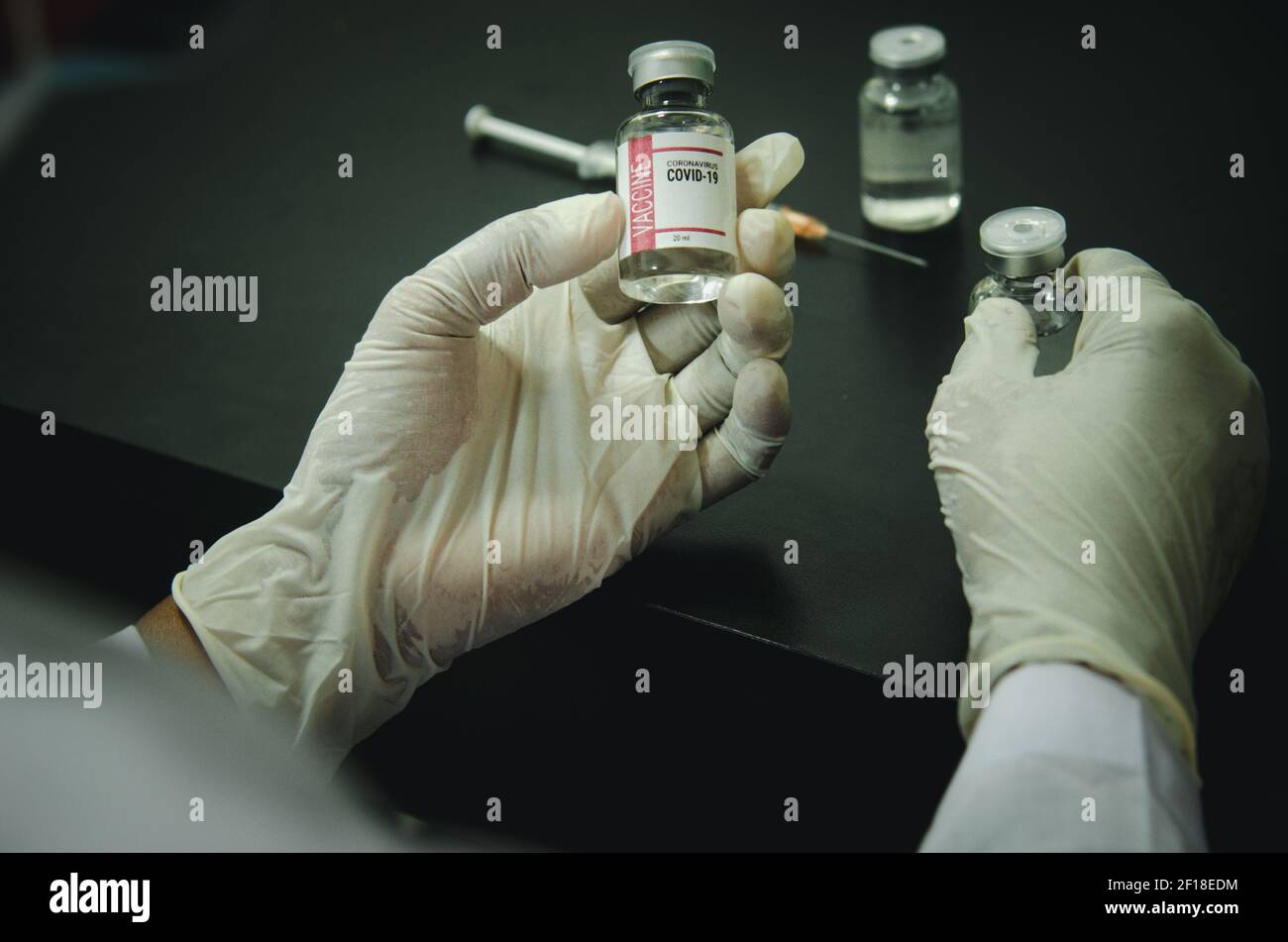 il medico o uno scienziato in un laboratorio esamina una fiala di vaccino del coronavirus: una malattia medica. Foto Stock