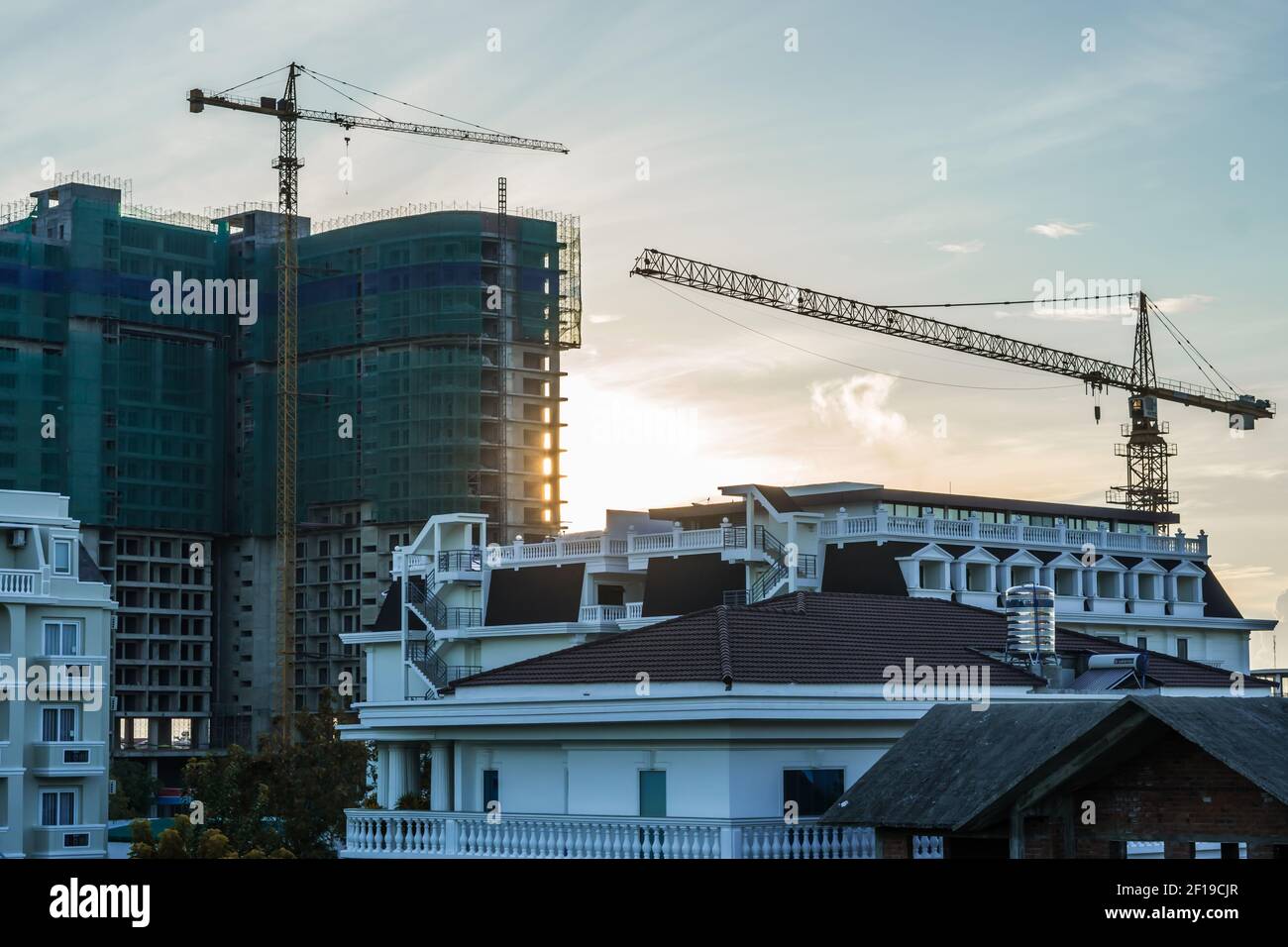 Edificio moderno, grande e a più piani, residenziale o con uffici, in costruzione, all'alba sullo sfondo del cielo, gru a torre. Settore immobiliare Foto Stock