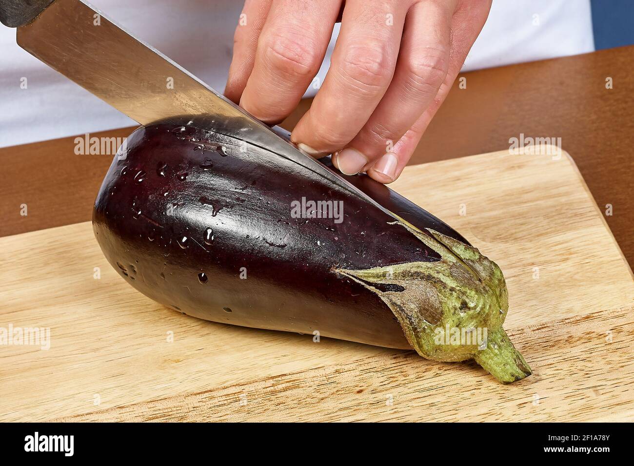 Cuocete le mani tagliando l'melanzana grande Foto Stock