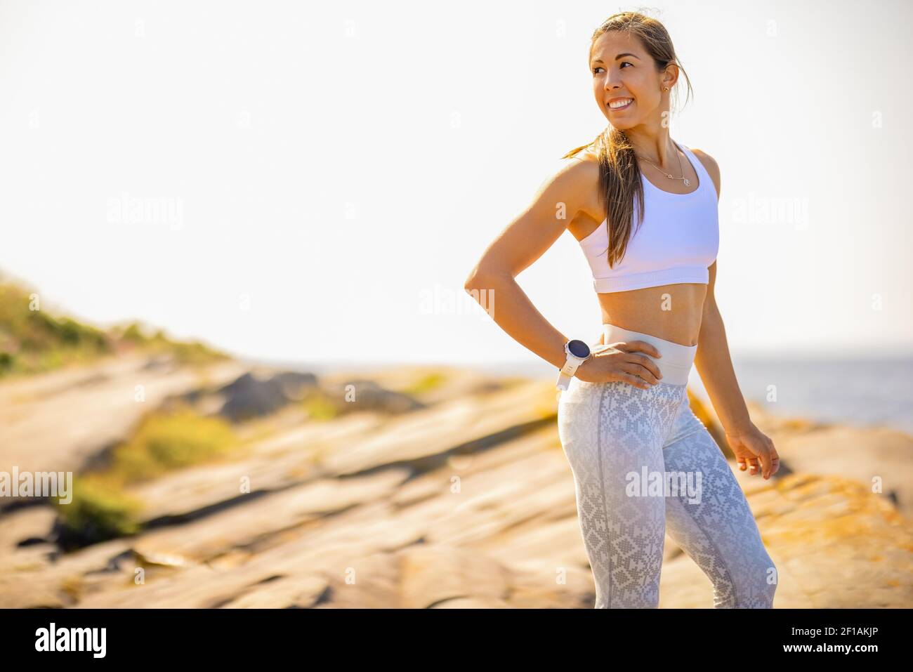 Fit Woman in piedi sulla roccia durante il giorno di sole Foto Stock
