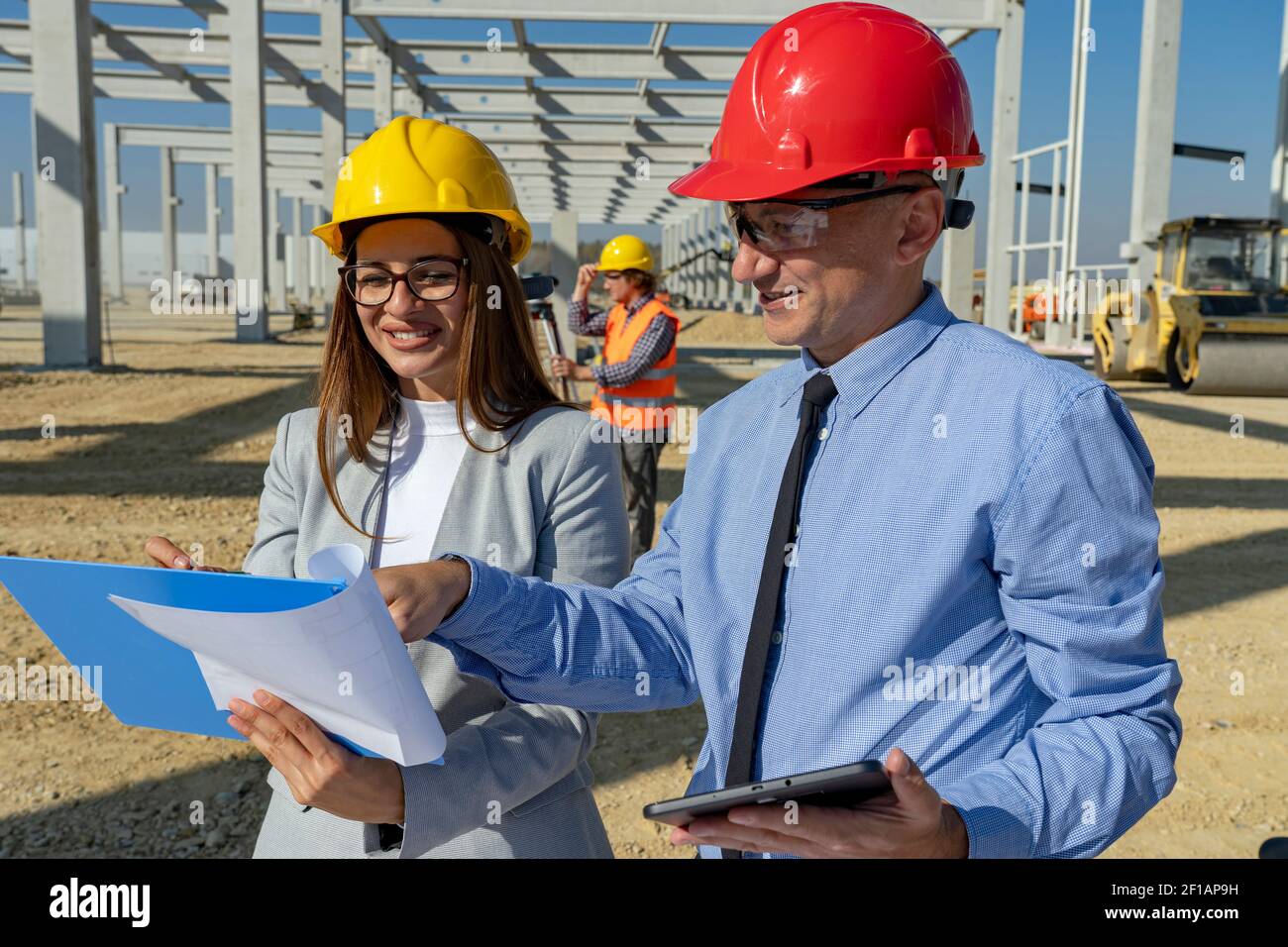 Sorridente architetto femminile e uomo d'affari maturo riunione sul cantiere. Relazione d'affari e concetto di lavoro di squadra. Foto Stock