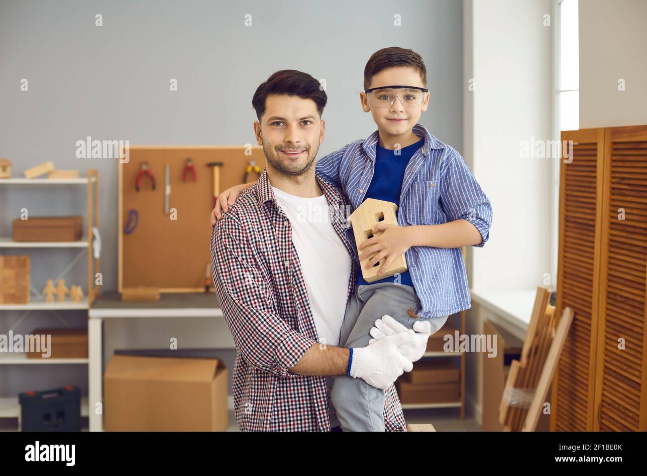 Ritratto di famiglia del giovane padre con il suo figlio preferito in officina o garage. Foto Stock