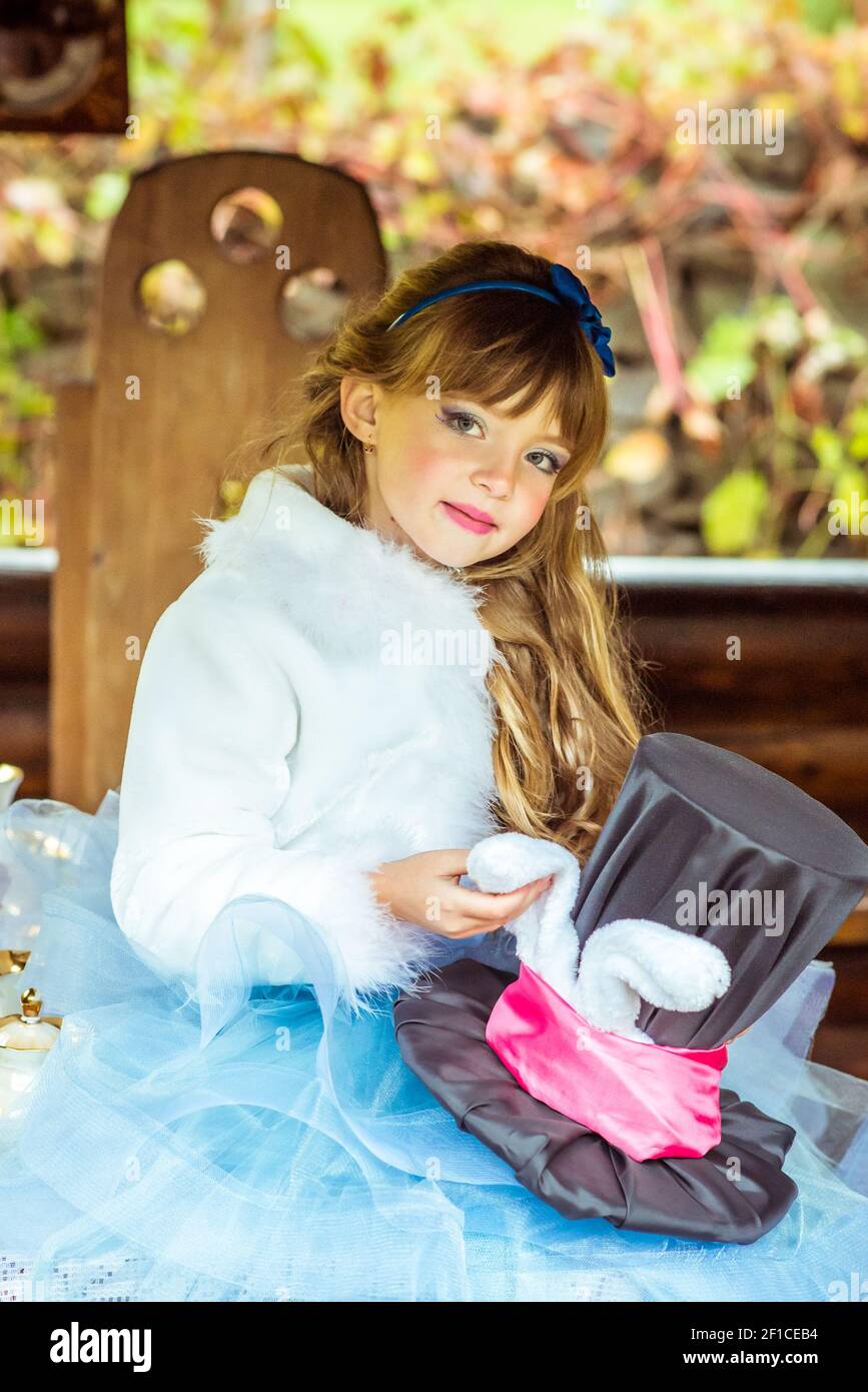 Un po' di bella ragazza con cappello a cilindro con orecchie come un  coniglio nelle mani al tavolo Foto stock - Alamy