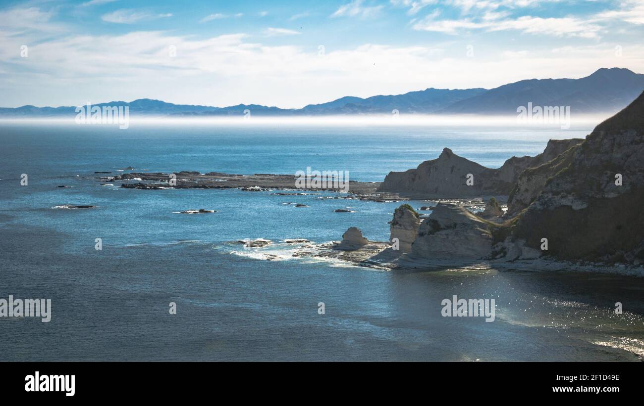 Seastacks con montagne frizzanti sullo sfondo, girato a Kaikoura, Nuova Zelanda Foto Stock