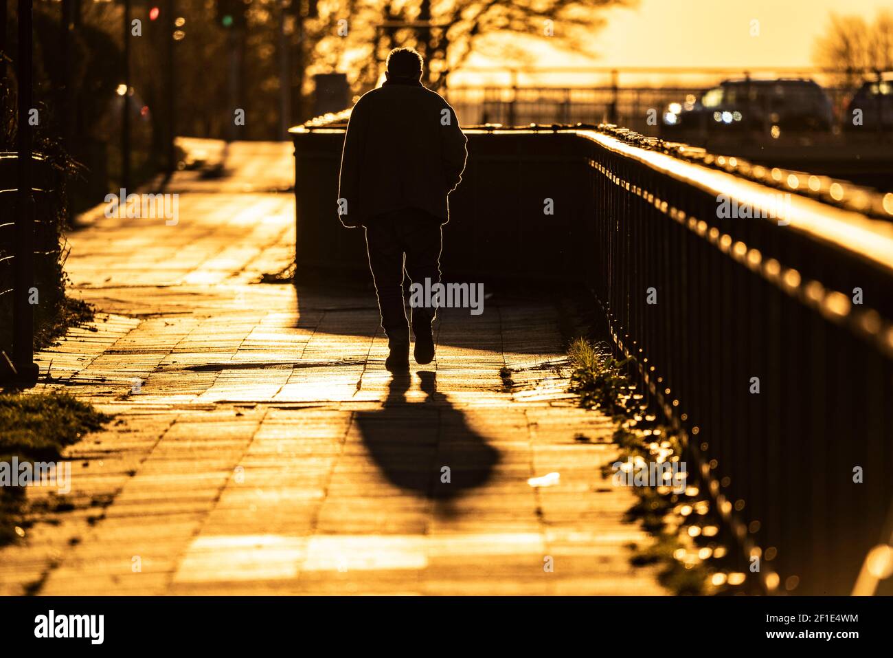 Uomo, anziano, camminando su un marciapiede, nel sole che tramonta, lunga ombra di getto, immagine simbolica, Essen, NRW, Germania Foto Stock
