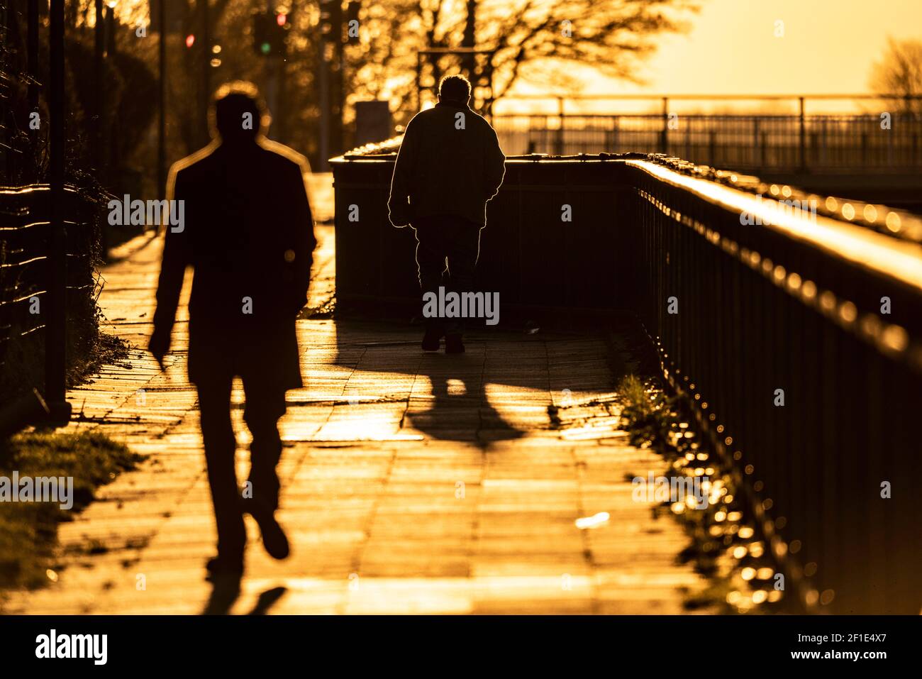 Uomo, anziano, camminando su un marciapiede, un secondo uomo che lo segue, nel sole che tramonta, lunga ombra gettata, immagine simbolica, Essen, NRW, Germania Foto Stock