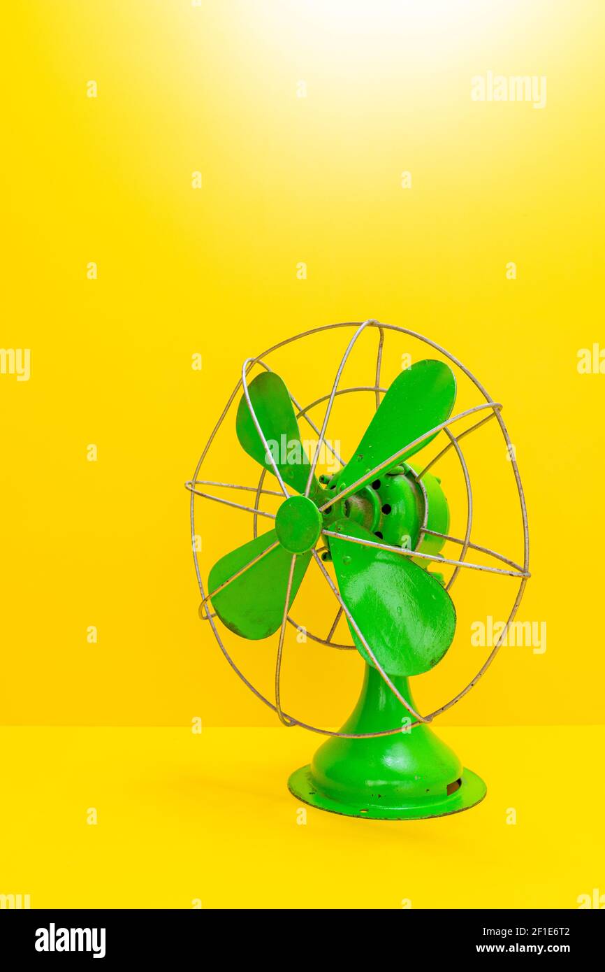 Vecchio ventilatore elettrico verde su sfondo giallo Foto Stock