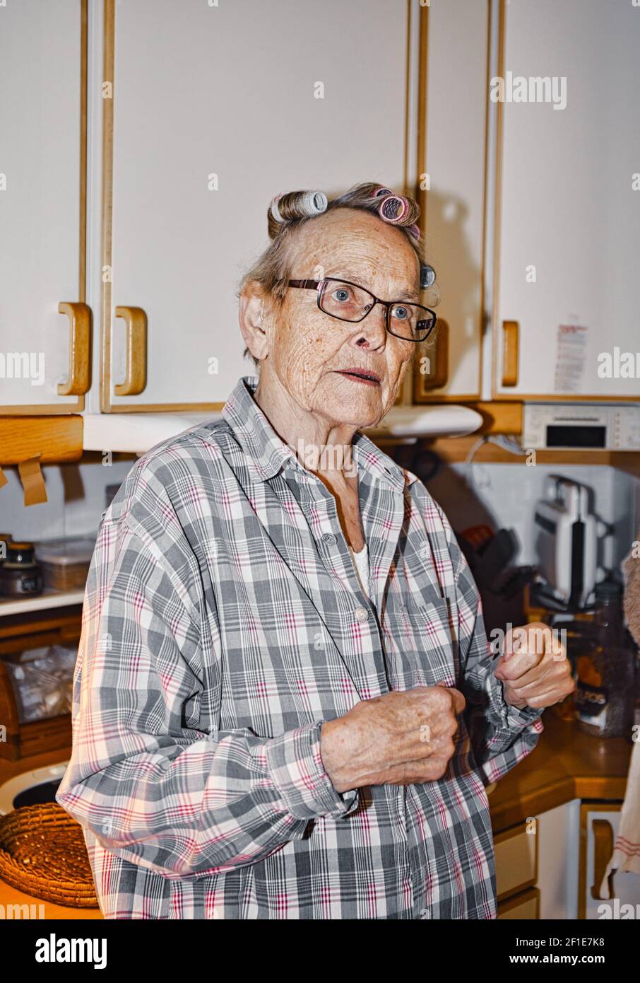 Anziana donna svedese anziana in arricciacapelli in cucina. Concetto di stile di vita Foto Stock