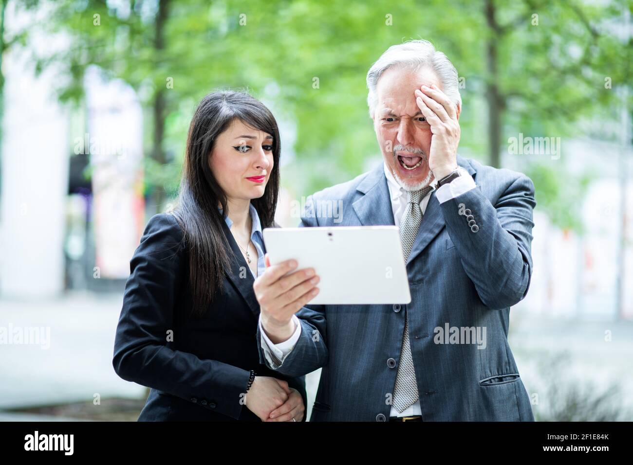 Coppia della gente di affari che usa un tablet outdoor che esprime male sensazioni Foto Stock