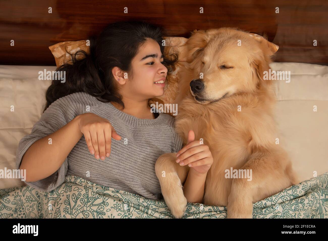 UNA RAGAZZA GIOVANE FELICE E CANE DI PET SDRAIATO SUL LETTO E GIOCARE L'UNO CON L'ALTRO Foto Stock