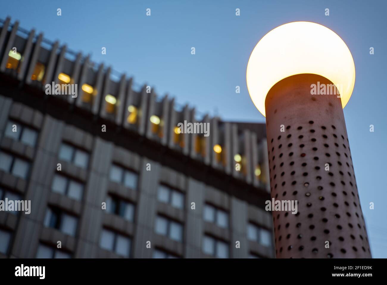 Una lampada pubblica di medie dimensioni all'aperto, con rivestimento in metallo e lampadina rotonda, di fronte all'hotel Park Inn Pribaltiyskaya a San Pietroburgo, Russia. Foto Stock