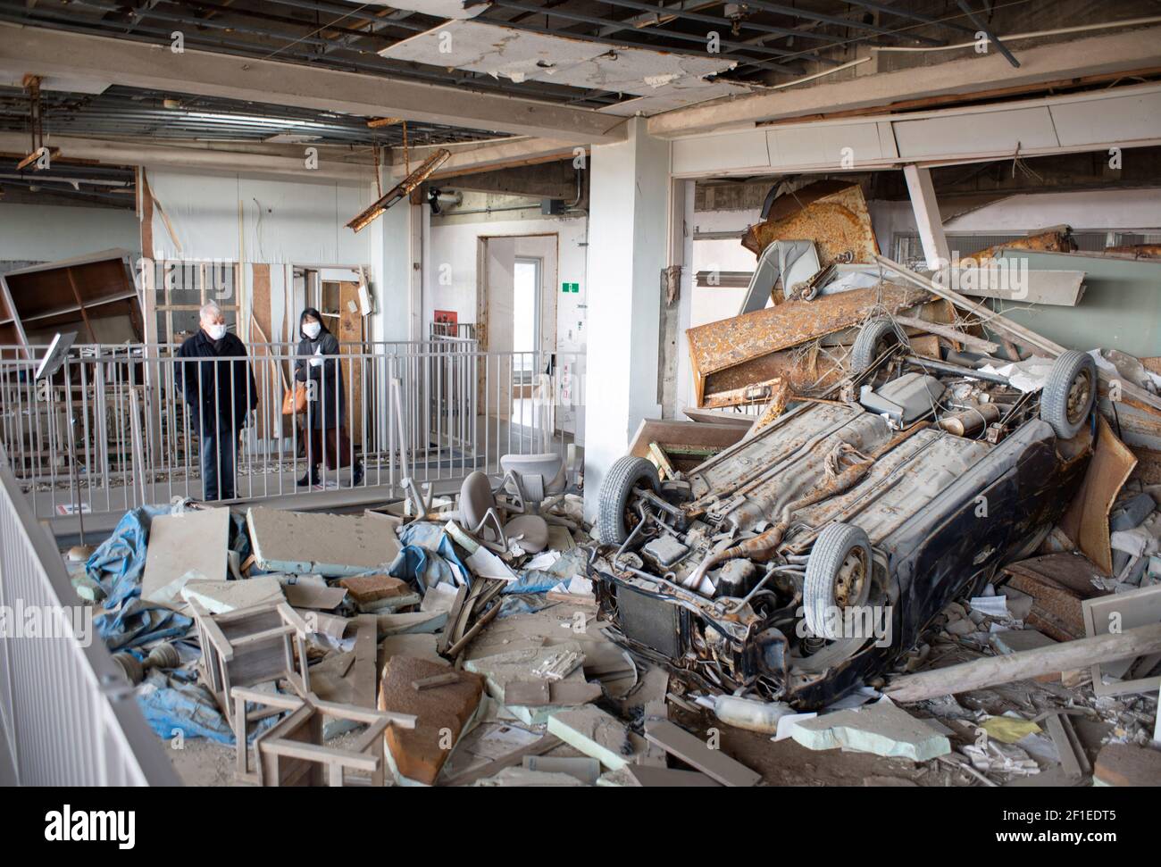 I visitatori si affacciano sugli interni martoriati della Koyo High School, che fa ora parte del museo commemorativo del terremoto e dello tsunami del marzo 2011 a Kesennuma, Prefettura di Miyagi, Giappone, il 19 febbraio 2021. Il 11 marzo 2021 ricorre il decimo anniversario del terremoto e dello tsunami che hanno devastato l'intera regione, portando oltre 18,000 vite umane e cancellando centinaia di migliaia di case, aziende, uffici pubblici e scuole. Fotografo: Robert Gilhooly Foto Stock