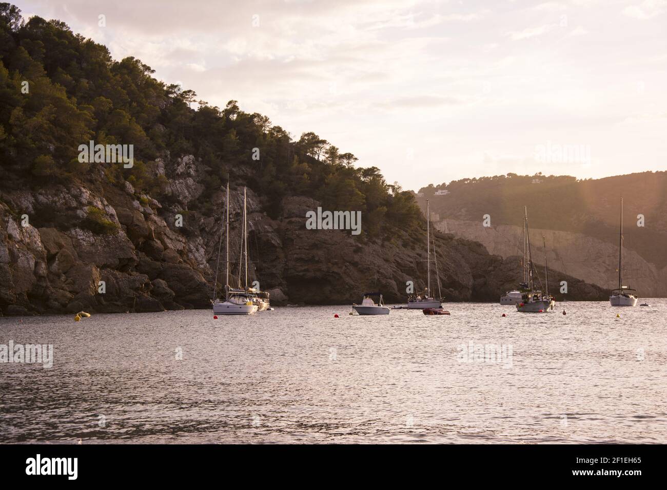 Barche al tramonto nella piccola baia di Cala Benirras, isola di Ibiza. Foto Stock